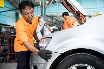 Skilled technician make refurbishment of bodywork in automotive car service, replacing or...