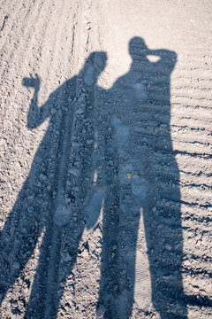 Shadows of two people on freshly plowed ground.
