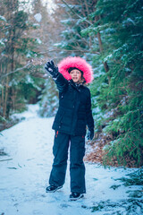 child with huge pink hood in forest in winter time