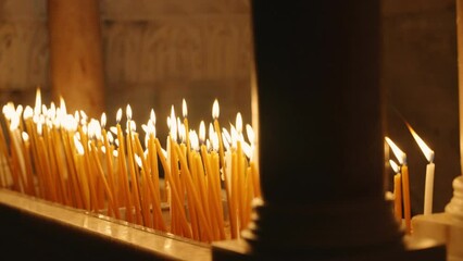 Burning candles in the Church of the Holy Sepulchre lighting the dark room. Visitors light candles in religious and most holy church in Old City of Jerusalem. Close up on yellow candles