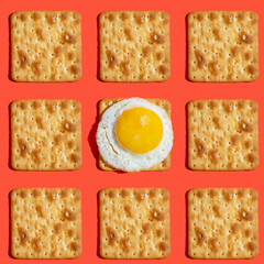 Seamless pattern with salty cracker and sunny side up egg on red background.