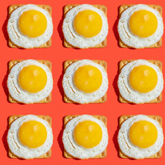 Seamless pattern with sunny side up egg on salty cracker over red background.