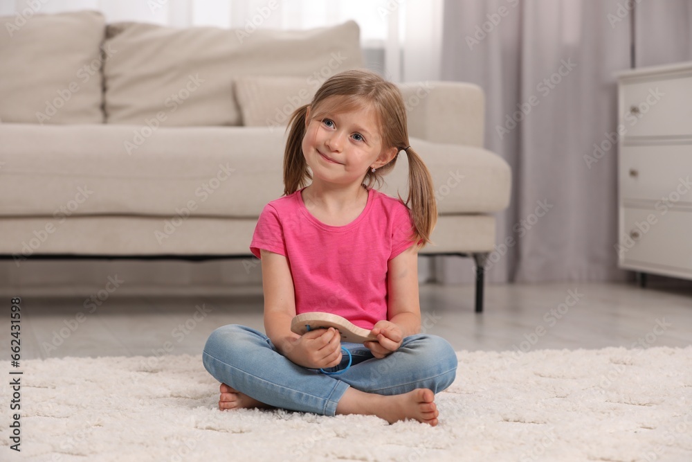 Sticker Cute little girl playing with wooden lacing toy indoors