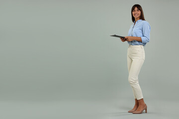 Happy secretary with clipboard on light grey background. Space for text