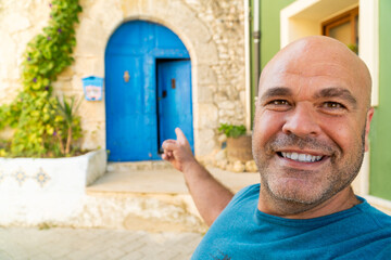  Smiling man takes a selfiewith a beautiful blue door on background - obrazy, fototapety, plakaty