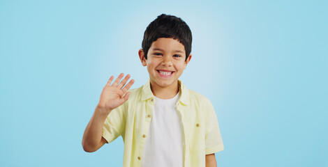 Kid, hand and waving with smile in studio on blue background in mockup with excitement. Youth, boy and greeting while looking at screen with face for announcement of offer on social media, web or app