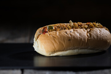 Hot dog on a black board on a wooden table