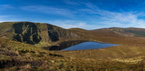 Beautiful vista, panorama with heart shaped lake, Lough Ouler, reflecting blue sky and Tonelagee Mountain. Hiking in Wicklow Mountains, Ireland