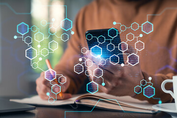 Man holding, using smartphone typing at office workplace with notebook. Concept of distant work, business education. Blockchain crypto hologram. Shot of hands.