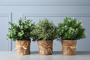 Different artificial potted herbs on light grey table