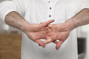Man cracking his knuckles on blurred background, closeup. Bad habit