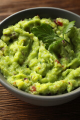 Bowl of delicious guacamole with parsley on table, closeup