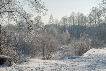 River in winter, stones in the snow and trees. Frost and winter atmosphere.