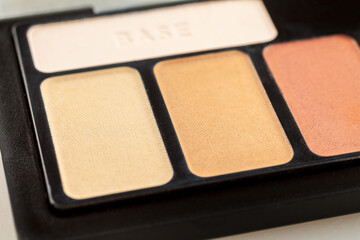 Women's palette with makeup shadows, highlighter base, selective focus