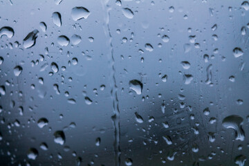 Drops of water on glass on a cold background, rainy weather high humidity, worsening weather forecast selective focus