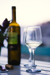 Wineglass with some white wine served on it on a blurry beautiful landscape in the background in Santorini, Greece