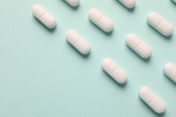 White pills on mint background, flat lay. Space for text