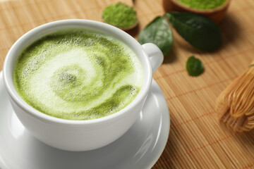 Delicious matcha latte in cup on bamboo mat, closeup. Space for text