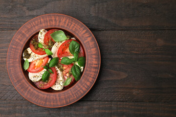 Plate of delicious Caprese salad with pesto sauce on wooden table, top view. Space for text