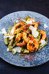 Traditional fried king prawns with Italian foglie di olivo pasta and parmesan cheese served as close-up on a design plate with text space