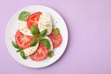 Plate of delicious Caprese salad with herbs on violet table, top view. Space for text