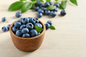 Bowl of fresh tasty blueberries on white wooden table, closeup. Space for text