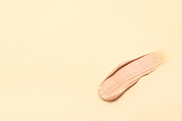 Smear of skin foundation on beige background. Space for text