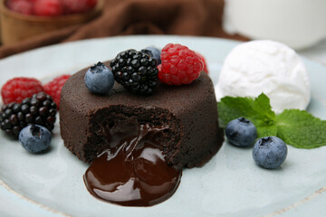 Delicious chocolate fondant served with fresh berries and ice cream on plate, closeup