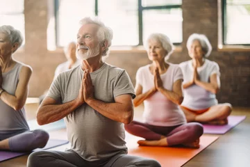 Poster A group of senior people stretching on yoga mats in studio. Senior people doing guided meditation and yoga in studio. Happy, healthy elderly people. © VisualProduction