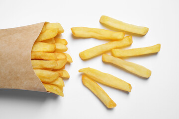 Paper cup with French fries on white table, flat lay