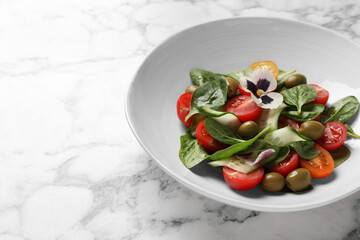 Delicious salad with vegetables and olives on white marble table. Space for text