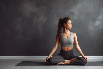 Foto auf Acrylglas Young woman doing yoga on yoga mat. Young woman exercising at home. Peaceful beautiful woman doing exercises at home in her studio. © VisualProduction