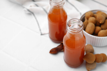 Tamarind juice and fresh fruits on white tiled table, space for text
