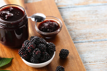 Fresh ripe blackberries and tasty jam on rustic wooden table. Space for text