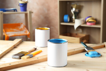 Cans of paints and brushes on wooden table indoors