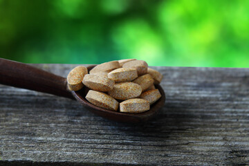 Herbal ayurvedic tablet or pills in wooden spoon isolated
