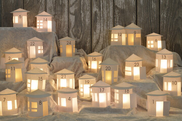 Advent calendar out of 24 self small made white round paper houses illuminated from the inside on...
