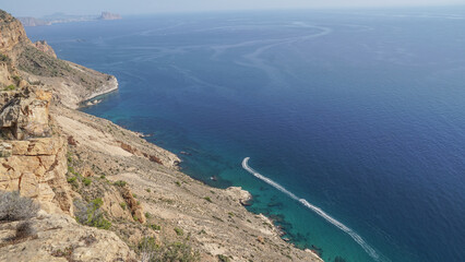Estelas de Motos de agua junto a u acantilado con aguas transparentes color turquesa 