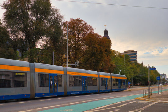 Moderne Niederflurstra&szlig;enbahn der LVB an der Haltestelle Thomaskirche vor herbstlicher Stadtkulisse mit Kirchturm, Stra&szlig;enbahn in Leipzig, Stadt Leipzig, Sachsen, Deutschland