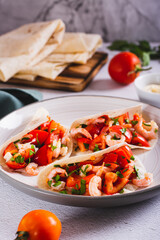 Vegetarian mini tacos with tomatoes, shrimp and herbs on a plate on the table vertical view