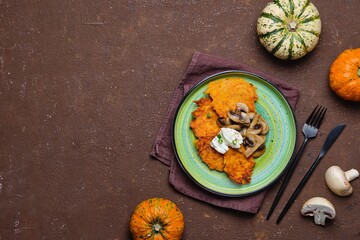 Pumpkin fritters with mushrooms and cream cheese on a green plate on a brown concrete background. Pumpkin recipes.