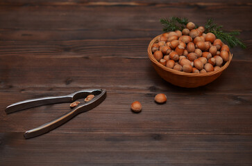 nutcracker and hazelnuts in a basket on a wooden background, space for an object