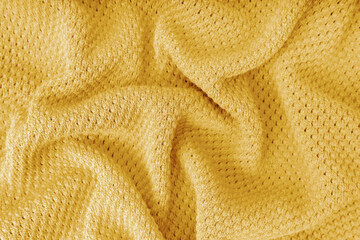 Yellow color crumpled, wrinkled knitting wool cloth texture. Background of knitted fabric with dots pattern. Textile structure, cloth surface, weaving of knitwear material.