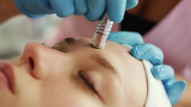 Beautician cosmetologist makes a procedure Microdermabrasion peeling of the face skin. Hardware cosmetology in clinic salon for client. Diamond face clean.
