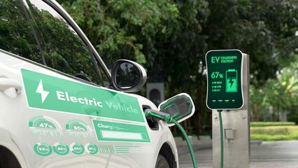Electric car plug into EV charger cable from charging station display smart digital battery status hologram in eco green park and foliage background. Energy sustainability technological advance.Peruse