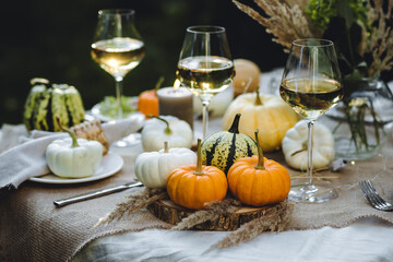 Fototapeta na wymiar Fall still-life. Orange pumpkins, dry flowers and candles on linen tablecloth. Dinner table outdoors in the garden. Cozy autumn concept., simple handmade decoration, countryside style