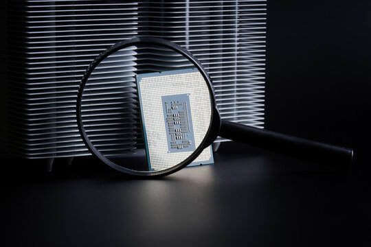 Modern powerful personal computer processor, a radiator for cooling it and magnifying glass. Research and analysis of quality, thermal conductivity, speed and power of the processor. Photo