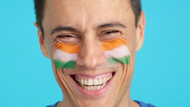 Man with a indian flag painted on the face smiling