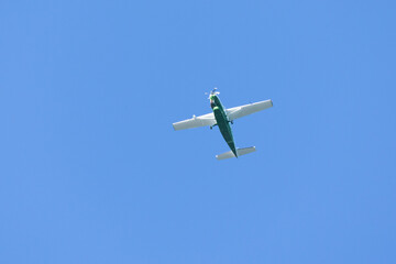 A green plane. A single engine plane crosses the blue sky. Transportation.