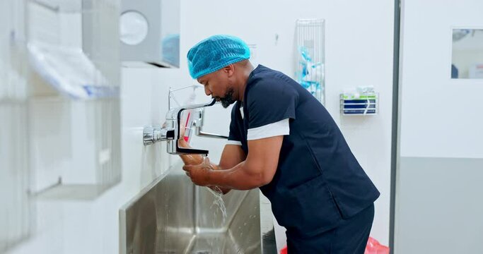 Surgeon cleaning hands, hygiene and doctor man, safety and water for washing away bacteria with healthcare. Health, wellness and African medical professional prepare for surgery with disinfection